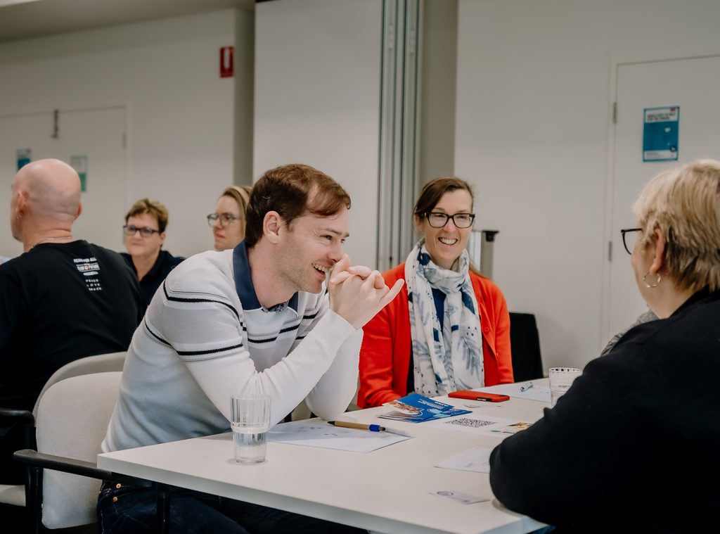Workshop participants smiling and talking together during Alike WA’s How to Facilitate a Support Group workshop.